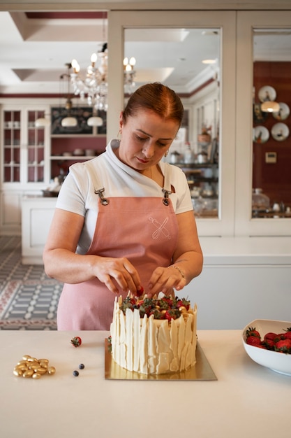 Pastelero femenino con un pastel de fresa en la pastelería