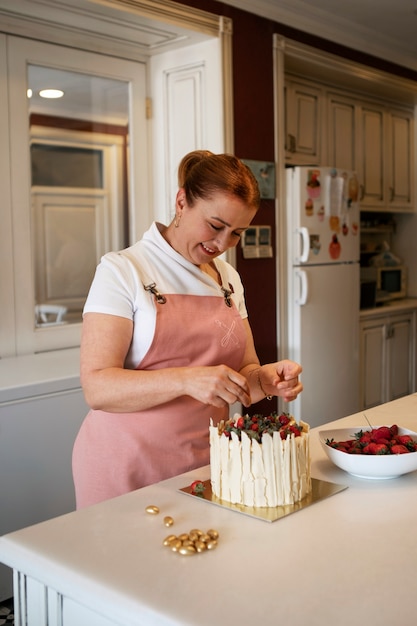 Pastelero femenino con un pastel de fresa en la pastelería