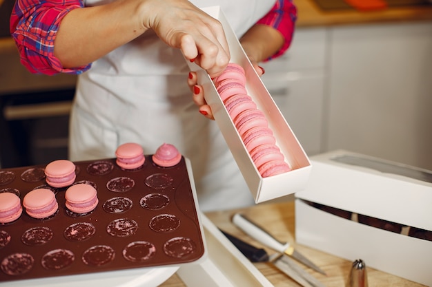 Pastelero en uniforme decora los macarrones