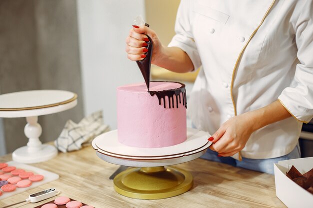 Pastelero en uniforme decora el pastel