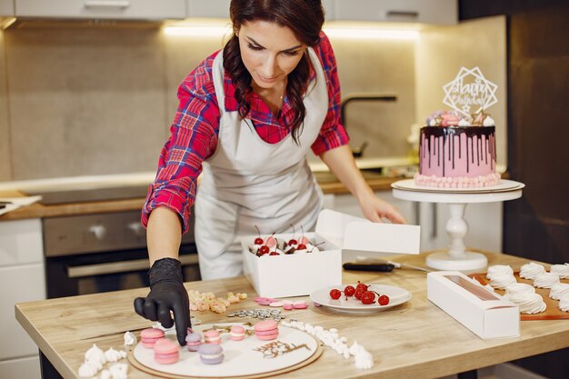 Pastelero en uniforme decora los pasteles