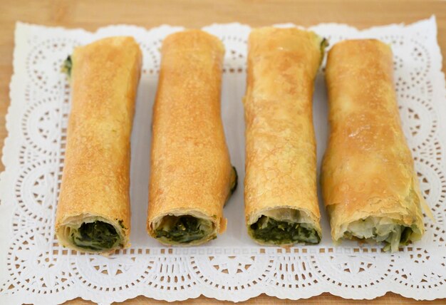 Pasteles rústicos icónicos rumanos y moldavos con verduras y relleno de espinacas colocados en una tabla de madera