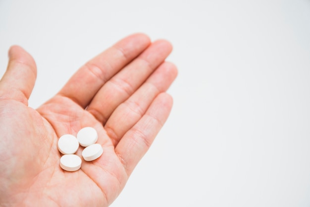 Pastillas blancas redondas en mano sobre el fondo blanco