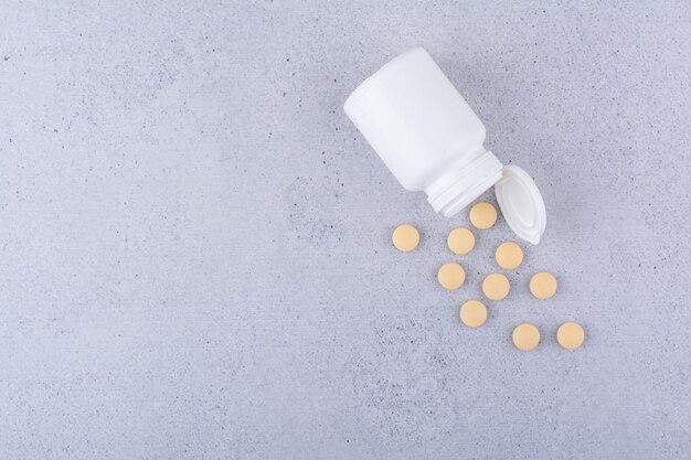 Pastillas farmacéuticas de recipiente de plástico blanco. Foto de alta calidad