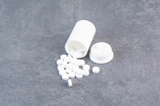 Pastillas médicas blancas de recipiente de plástico.