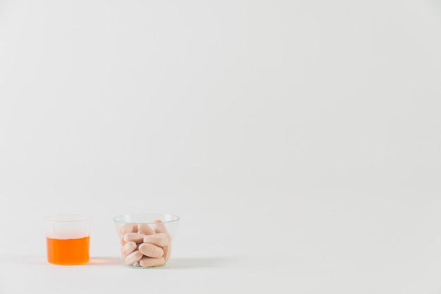 Pastillas y medicina en vaso pequeño