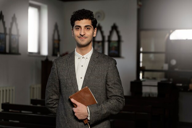 Pastor joven de tiro medio sosteniendo la biblia