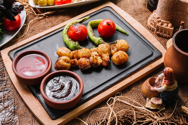 Patata al horno sobre tabla de madera con salsas de tomate pimiento vista lateral