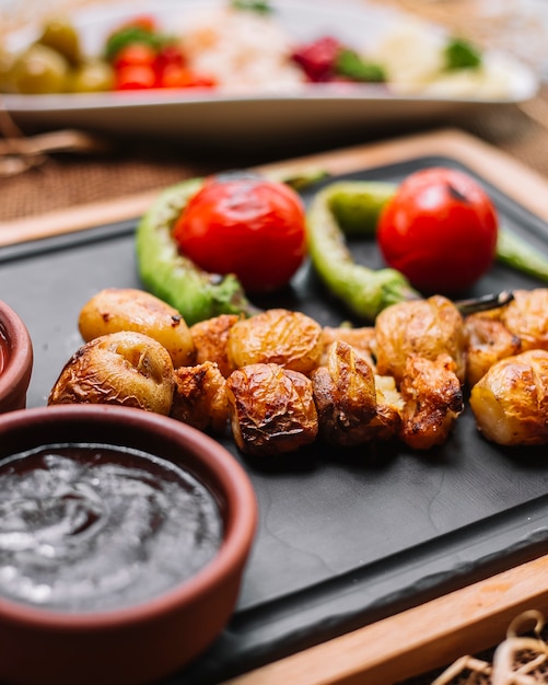 Patata al horno sobre tabla de madera con salsas de tomate pimiento vista lateral