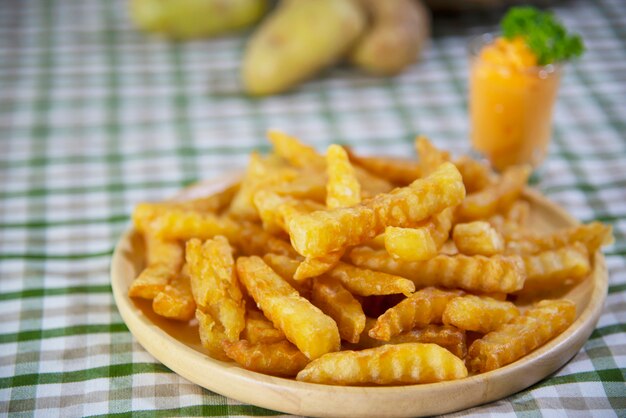 Patata frita deliciosa en un plato de madera con salsa bañada - concepto tradicional de comida rápida