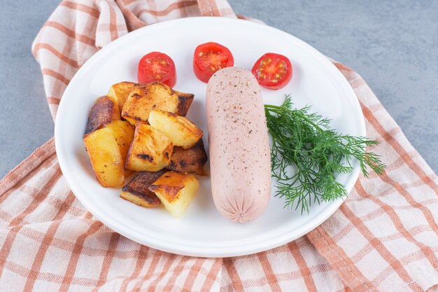 Patata frita y salchicha picante en un plato blanco.