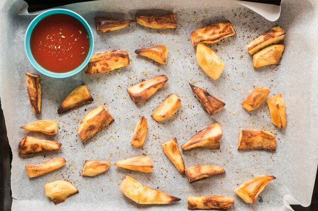 Patatas asadas con salsa de tomate sobre papel horneado.