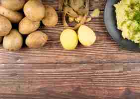 Foto gratuita patatas crudas sobre fondo de madera con espacio de copia