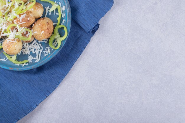 Patatas fritas decoradas con queso y pimienta en placa azul.