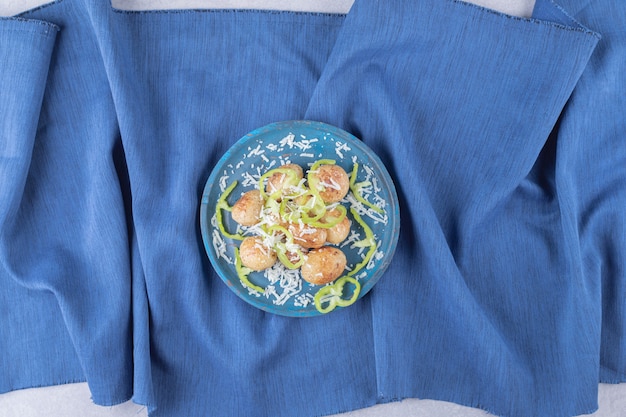 Patatas fritas decoradas con queso y pimienta en placa azul.