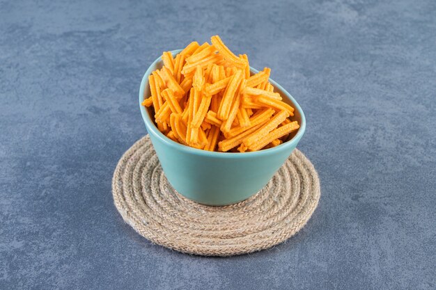 Patatas fritas dulces en un recipiente sobre salvamanteles, sobre el fondo de mármol.