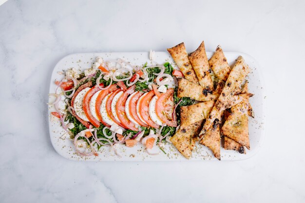 Patatas fritas con ensalada verde, vegetales y rodajas de tomate.