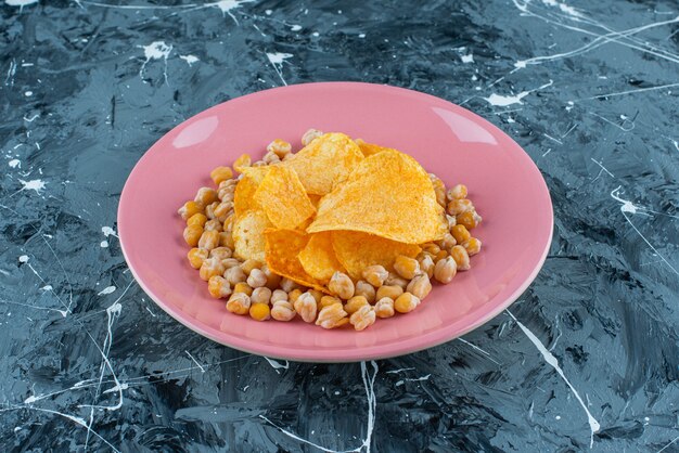 Patatas fritas y garbanzos en un plato, sobre la mesa azul.