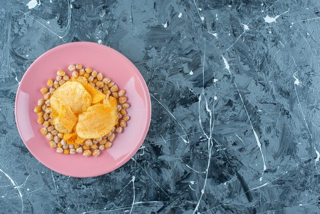 Patatas fritas y garbanzos en un plato, sobre la mesa azul.