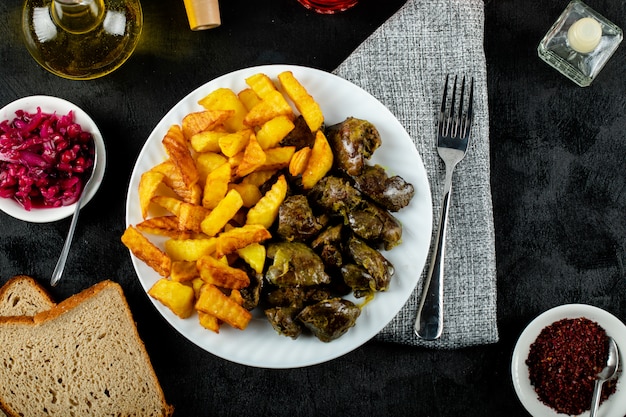 Patatas fritas con hígado a la parrilla en plato blanco servido con sumakh