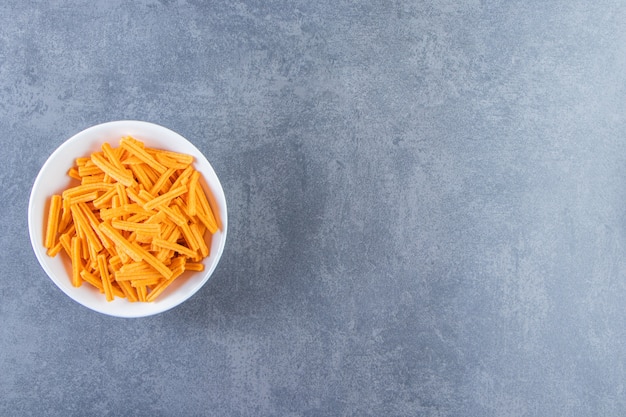 Patatas fritas en un recipiente sobre la superficie de mármol