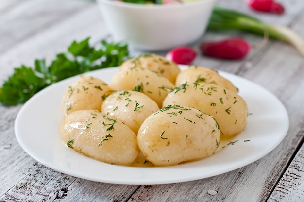 Patatas hervidas con mantequilla y eneldo en un plato blanco