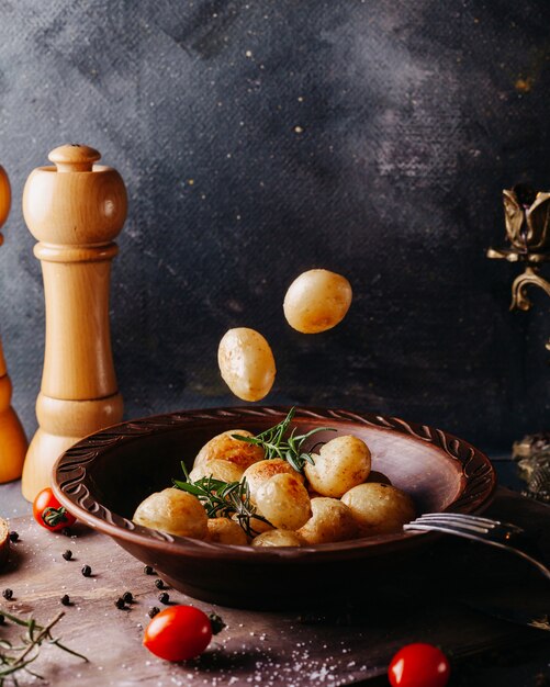 Patatas hervidas saladas dentro de un plato redondo marrón en la superficie gris