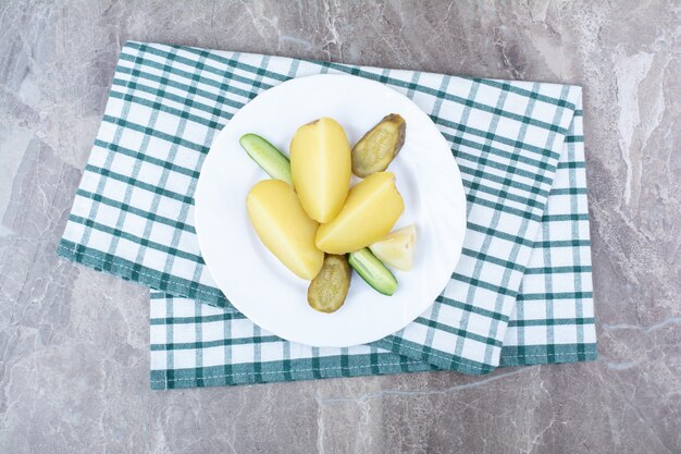 Patatas hervidas y varios encurtidos en un plato blanco.