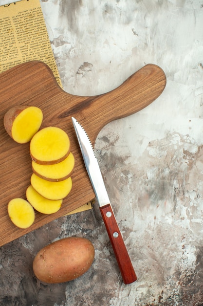 Foto gratuita patatas picadas en la tabla de cortar de madera en un periódico antiguo sobre fondo de colores mezclados