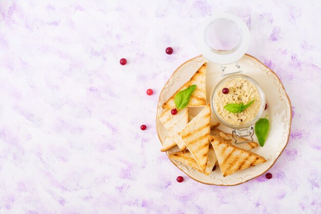 Paté de pollo, tostadas y hierbas en un plato