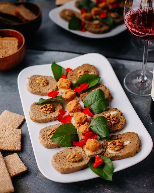 paté vegetal formado junto con hojas verdes dentro del plato blanco junto con patatas fritas de vino tinto en gris