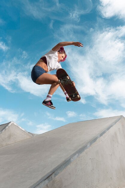 Patinador de tiro completo saltando con tabla en el parque