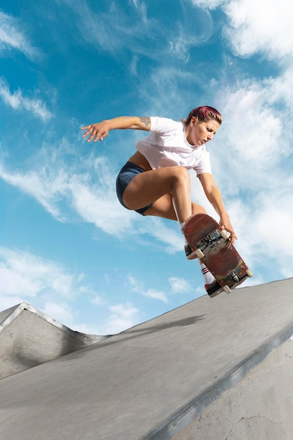 Patinador de tiro completo saltando con tablero al aire libre