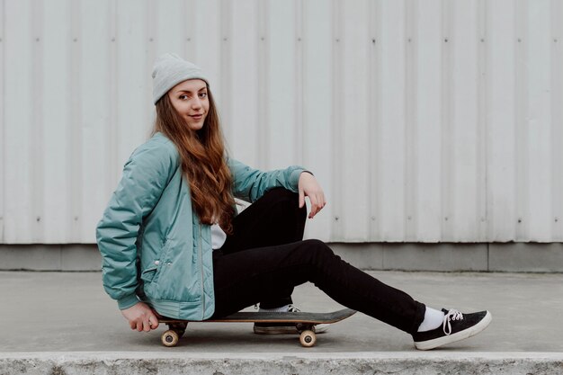 Patinadora sentada junto a su patineta al aire libre