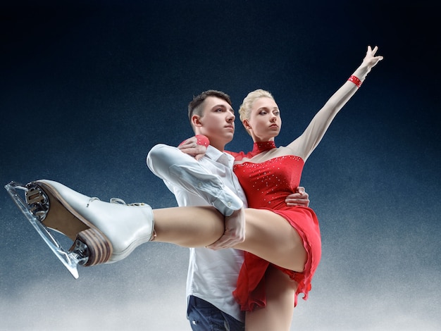 Patinadores artísticos profesionales de hombre y mujer que realizan espectáculo o competencia en la arena de hielo