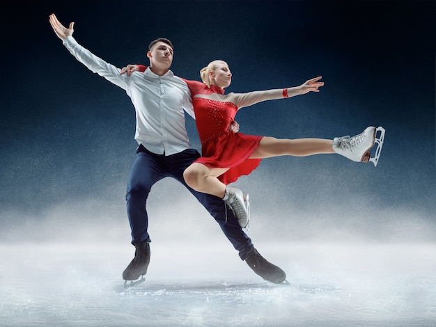 Patinadores artísticos profesionales de hombre y mujer que realizan espectáculo o competencia en la arena de hielo