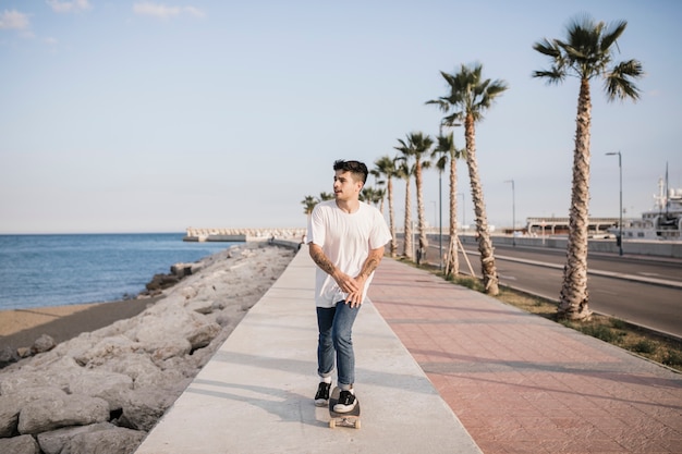 Patinaje masculino joven en el pavimento con patín