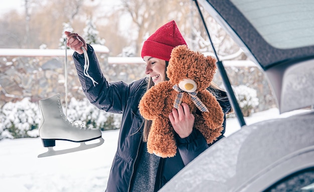 Patines viejos y un oso de peluche en manos de una mujer joven en invierno