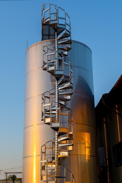 Patio de la bodega al atardecer con tanques de almacenamiento de vino de metal