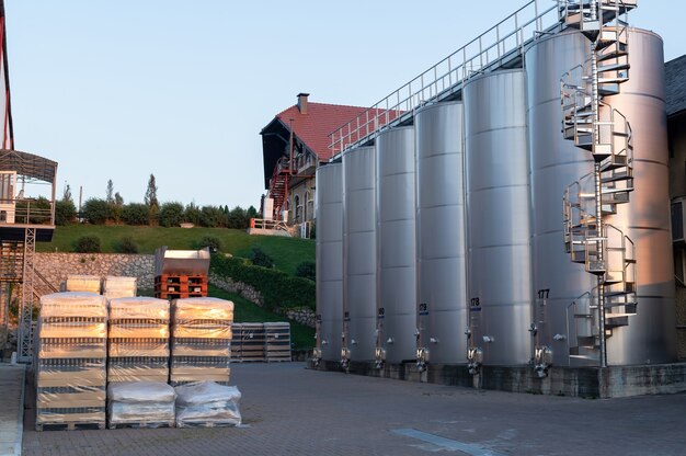 Patio de la bodega al atardecer con tanques de almacenamiento de vino de metal