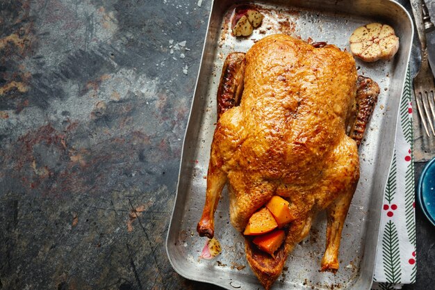 Pato asado al horno con verduras en sartén sobre fondo de piedra. Vista superior.