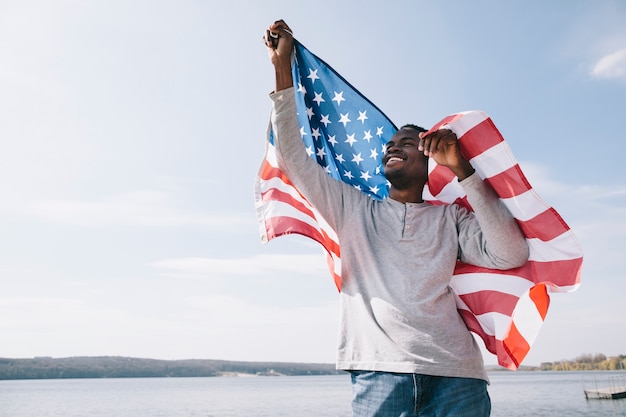 Patriota afroamericano feliz sosteniendo la bandera de Estados Unidos