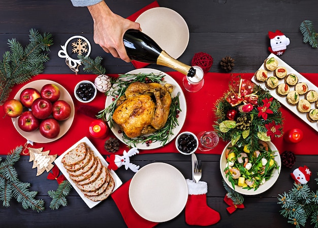 Pavo al horno Cena de Navidad. La mesa de Navidad se sirve con un pavo, decorado con brillantes guirnaldas y velas. Pollo frito, mesa. Cena familiar. Vista superior