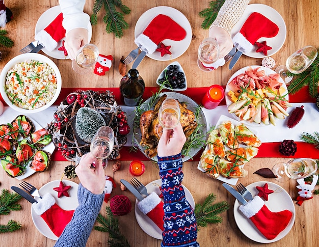 Pavo al horno. Cena de Navidad. La mesa navideña se sirve con un pavo, decorado con oropeles brillantes y velas. Pollo frito, mesa. Cena familiar. Vista superior, manos en el marco
