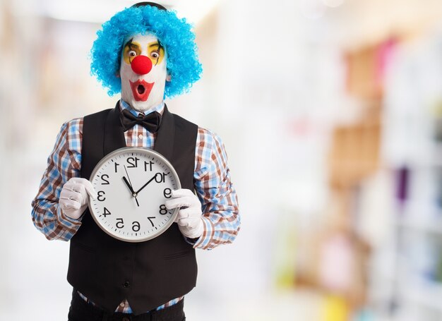 Payaso con cara graciosa sujetando un reloj