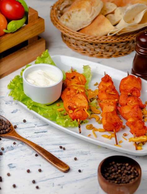 Pechuga de pollo bbq, shish kebab con verduras, hierbas y sumakh y yogurt en plato blanco.