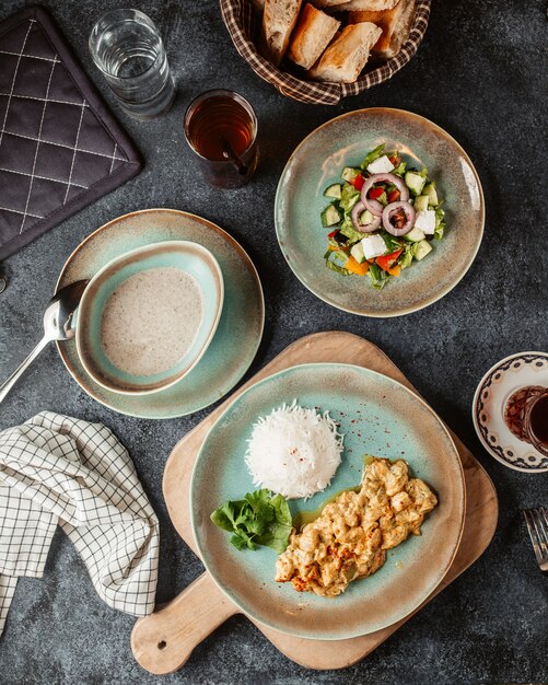 Pechuga de pollo picada preparada con salsa y servida con ensalada de arroz y sopa