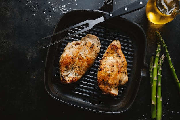 Pechuga de pollo sabrosa y apetitosa frita servida en una sartén con espárragos Fondo oscuro