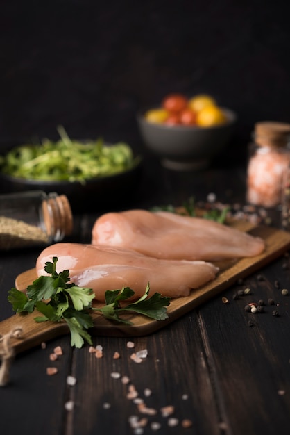 Foto gratuita pechuga de pollo sobre tabla de madera con ingredientes