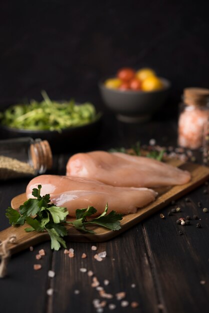 Pechuga de pollo sobre tabla de madera con ingredientes